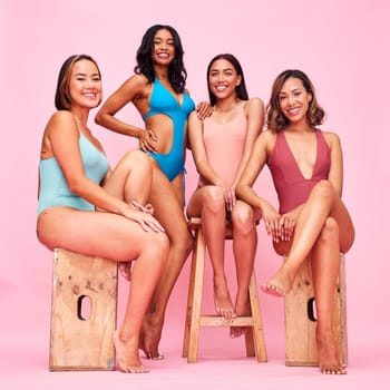 Bikini, portrait and group of women on stool in studio isolated on a pink background. Swimwear, happy and friends with body positivity, inclusion and diversity in summer fashion at beach vacation.