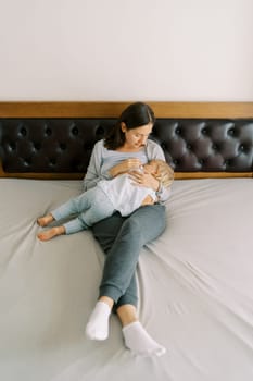 Mom breastfeeds a little girl, lying with her on the bed. High quality photo