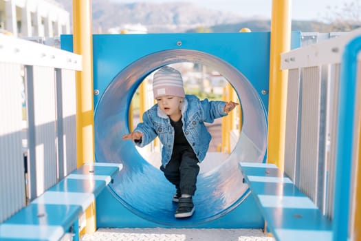 Little girl walks balancing through a pipe on a slide. High quality photo