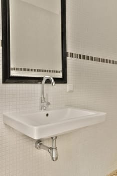 a bathroom with white tiles and black trim on the wall above the sink is a mirror that hangs over it