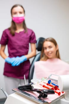 Close up tools for teeth whitening with happy patient and dentist on the background.