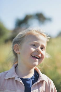 A five-year-old girl laughs outside in summer