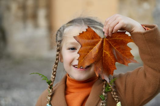 A girl with pigtails holding a maple leaf