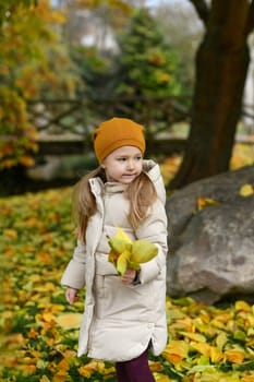 Girl holding yellow leaves in the autumn park