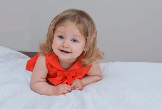 Portrait of a two year old girl with blue eyes in a red dress