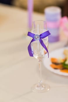 Close-up of wedding decorated champagne glass on the table.