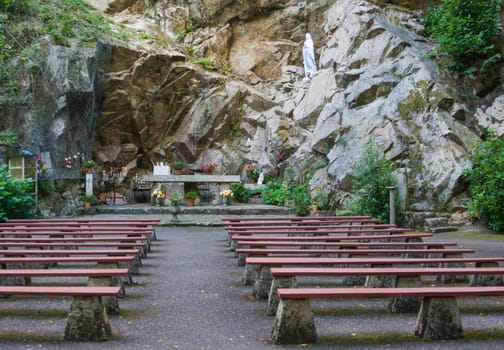 Cave grotto with the benches for prayer under open-air