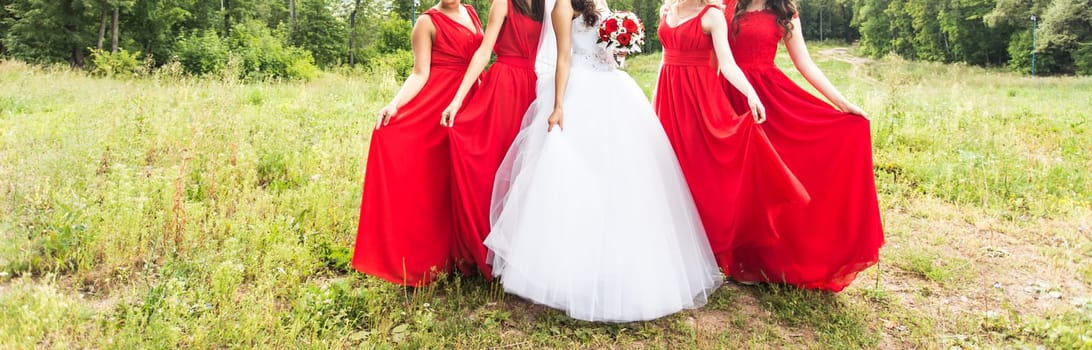 Bride with bridesmaids on the park on the wedding day.