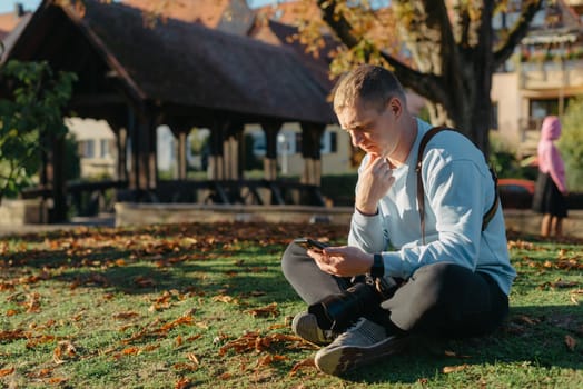 Professional photographer taking picture of beautiful autumn park. man professional photographer sit with camera in autumn park