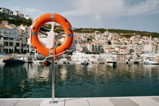 Orange lifebuoy on a stand on the coast of Lustica Bay. Montenegro. High quality photo