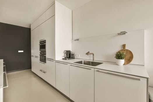 a modern kitchen with white cabinets and black wall behind the countertop is an oven, sink and dishwasher
