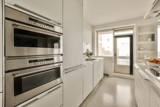 a kitchen with two ovens and an open door leading to the outside space in front of the counter area