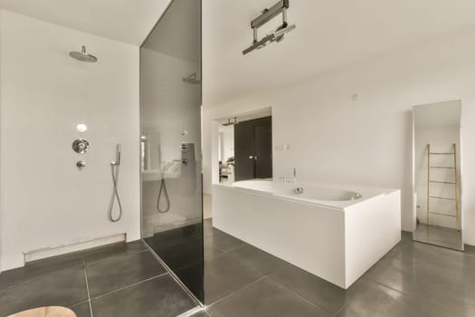 a modern bathroom with white walls and black tiles on the floor, there is a large mirror in the corner