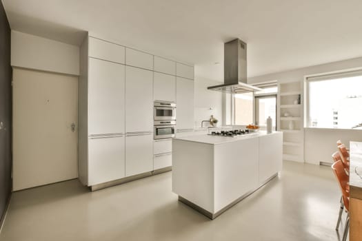 a kitchen and dining area in a modern style home with white cabinets, stainless appliances and an orange chair on the floor