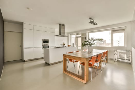 a kitchen and dining area in a modern apartment with white walls, flooring and an island table surrounded by orange chairs