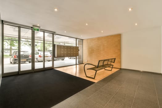 an outside area with a bench and glass door that leads to the parking lots of cars are parked in the garage