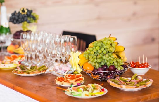 Table with cold snacks and tableware on luxury stand-up party