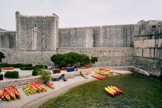 Colorful kayaks lie on the shore near the fortress wall. Dubrovnik, Croatia. High quality photo