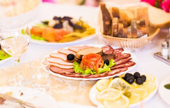 platter of sliced ham,salami and cured meat with vegetable decoration on festive table.