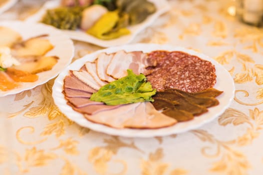 platter of sliced ham,salami and cured meat with vegetable decoration on festive table.