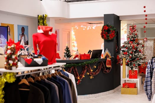 Beautifully decorated clothing store ready to spread holiday spirit in shopping center, welcoming customers with christmas tree and ornaments. Xmas decor fashion boutique during winter season.