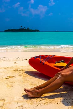 Canoe boat on the white sand of the turquoise sea and sexy womens feet on Rasdhoo island in Rasdhoo Atoll Maldives.