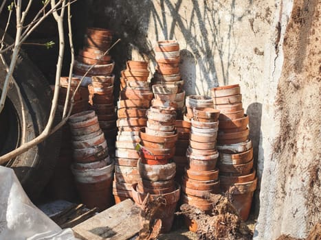 Many different old and dirty clay pots standing in rows and stuffed into each other on a spring day in the backyard of a house on an autumn day, side view close up. Concept for home renovation, construction work, home.