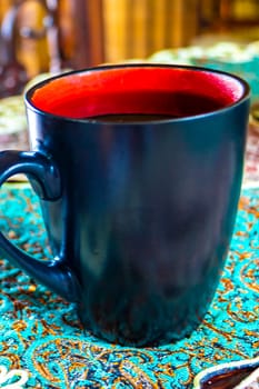 Red and black coffee cup on an elegant turquoise tablecloth in Para Heredia Costa Rica in Central America.