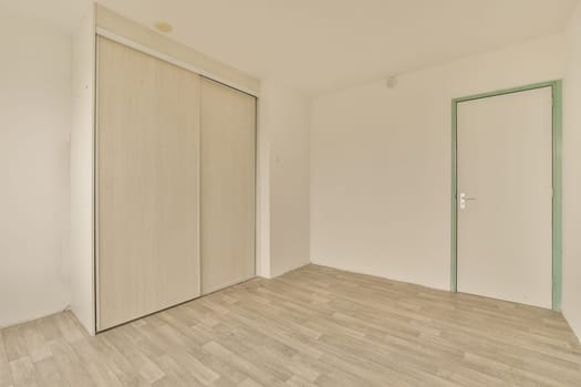 an empty room with white walls and wood flooring the door is open on the right side of the room