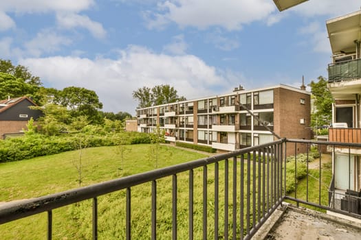 an apartment complex with green grass and trees in the foreground area on a sunny day, taken from a balcony