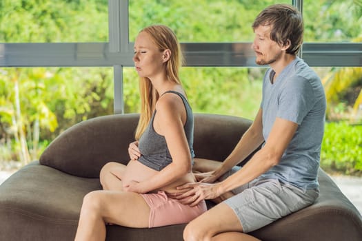 health, pregnancy and happy people concept - husband giving his wife back massage at home.