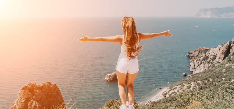 Woman travel sea. Young Happy woman in a long red dress posing on a beach near the sea on background of volcanic rocks, like in Iceland, sharing travel adventure journey