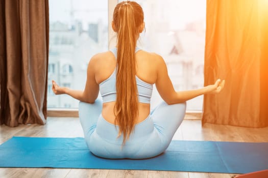 Young woman meditating at home. Girl practicing yoga in class. Relaxation at home, body care, balance, healthy lifestyle, meditation, mindfulness, recreation, workout, fitness, training concept.