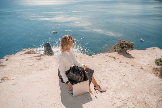 Freelance women sea working on a computer. Pretty middle aged woman with computer and phone outdoors with beautiful sea view. The concept of remote work