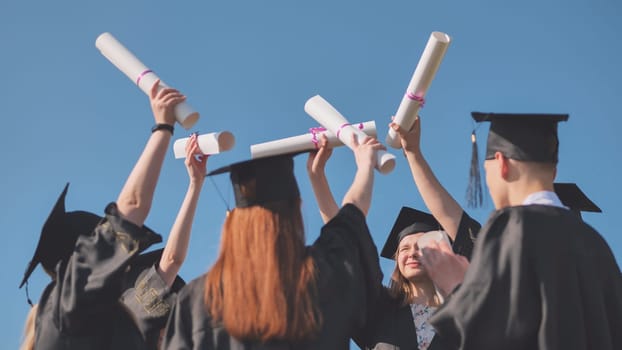 College graduates join hands with their diplomas. The concept of friendship