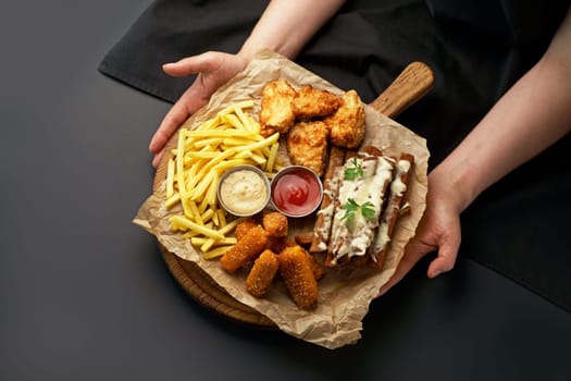 chicken fillet fried in batter with sauce on a wooden board on a black background