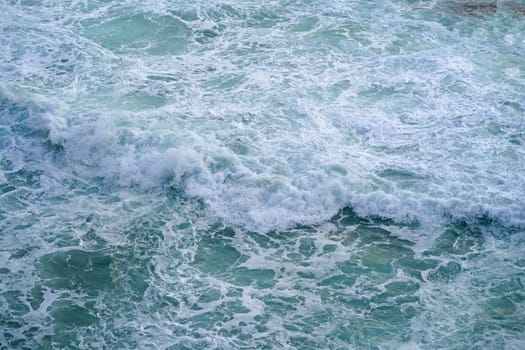 Waves crashing on seashore rocks,Top view sea surface waves background