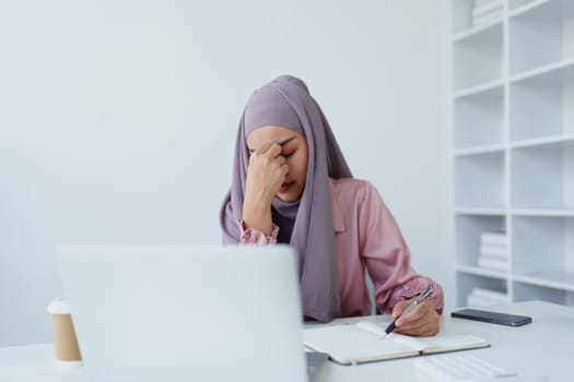 Muslim female employee working in office burnout