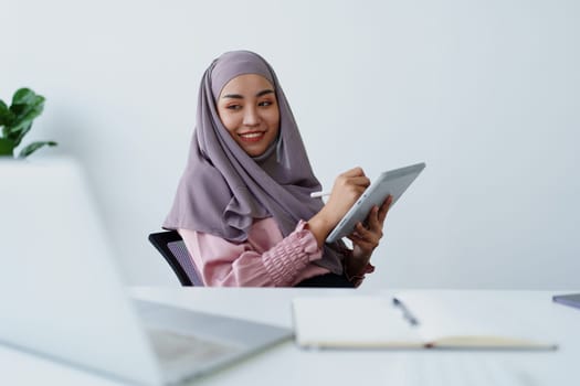 Muslim women use tablet computers, and laptops to check their accounts at work