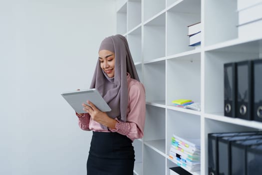 Female Muslim employee uses tablet to work at office