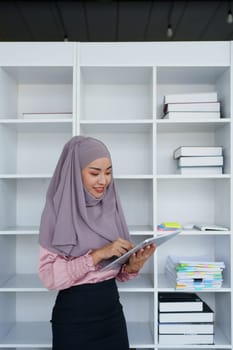 Female Muslim employee uses tablet to work at office