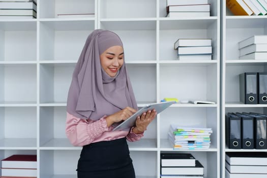 Female Muslim employee uses tablet to work at office