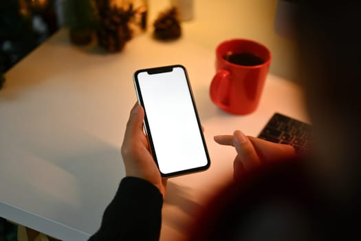 Closeup young woman using mobile phone sitting at desk in cozy home.