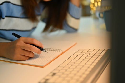 Cropped shot of young woman writing notes in personal daily planner, planning workday.