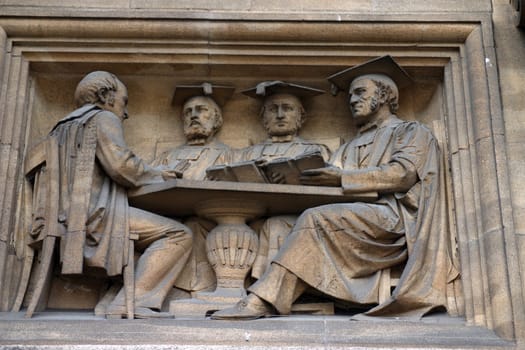 Detail of a sculpture showing dons on the University of Oxford's Examination Schools Building