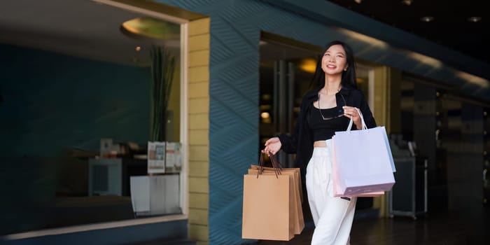 Happy beautiful young stylish woman asian with shopping bag while walking in the mall on holiday Black Friday.