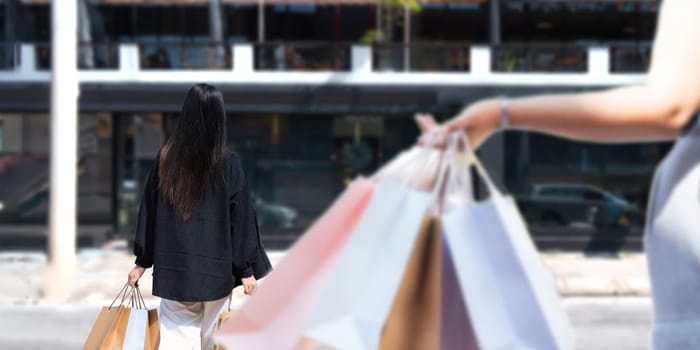 Happy beautiful young stylish woman asian with shopping bag while walking near mall on holiday Black Friday.