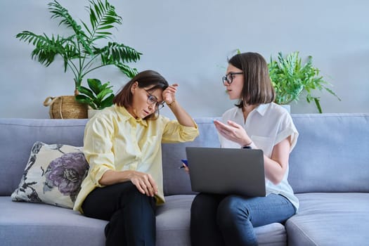 Middle aged woman in individual therapy, female psychologist and patient sitting together on couch in office. Psychology, counseling, psychotherapy, mental health, health care, mature people concept