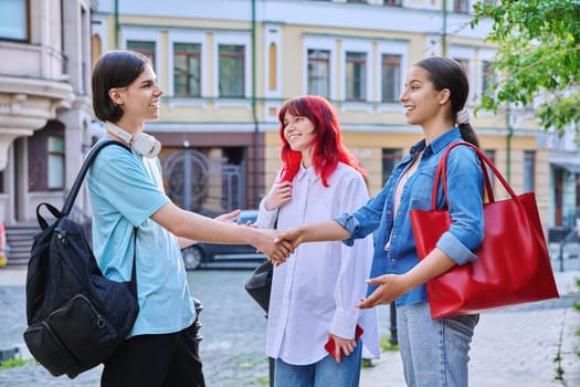 Meeting teenage friends outdoor, on street of city. Happy laughing talking young females and guy. Youth, communication, friendship, emotions, high school, college concept