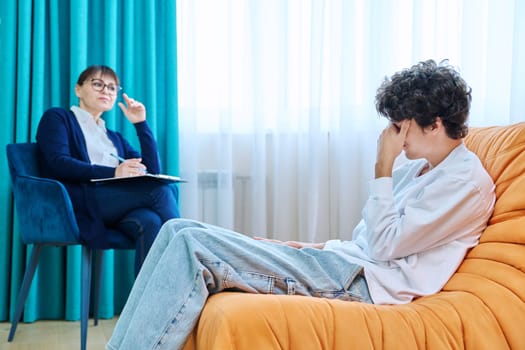 Female psychologist therapist counselor social worker talking to young male, individual therapy session. Mental health support psychology psychotherapy concept